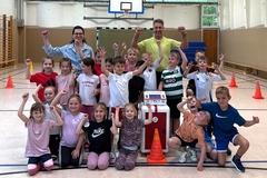Jubelnde Kinder in einer Sporthalle mit Lehrer und der Beigeordneten Alexandra Adel.