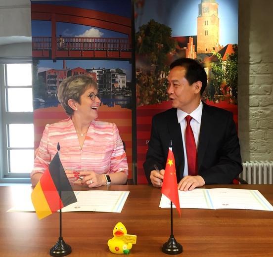 Der stellvertretende Generealsekretär der Weixian Regierung Qingjie An und Oberbürgermeisterin Dietlind Tiemann unterzeichnen Erklärung zu interkommunaler Zusammenarbeit