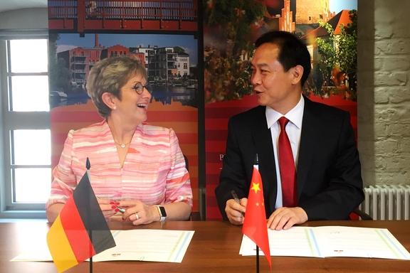 Der stellvertretende Generealsekretär der Weixian Regierung Qingjie An und Oberbürgermeisterin Dietlind Tiemann unterzeichnen Erklärung zu interkommunaler Zusammenarbeit