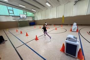 Kind sprintet in einer Sporthalle einen Parcour ab