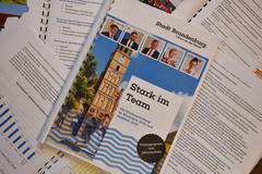 mehrere bedruckte Seiten liegen durcheinander, in der Mitte das Deckblatt der Pressemappe mit dem Titel "Stark im Team"