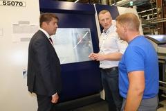 Steffen Scheller lässt sich vom Fertigungsleiter Sebastian Lempe und einem Facharbeiter die Produktion eines Teiles erklären.