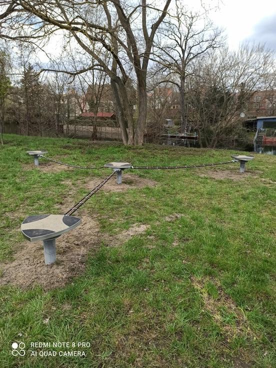 Spielgerät auf Rasenfläche: drei Slacklines gehen von einem Mittelpunkt aus in drei Richtungen, in der Mittel und an den Rändern sind Standfächen