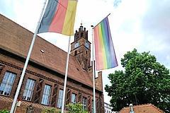 Deutschland- und Regenbogenflagge wehen vor dem Rathaus