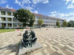 Schulgebäude mit Skulptur mit zwei Schülern.
