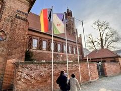 Drei Frauen laufen am rathaus vor Trauerbeflaggung