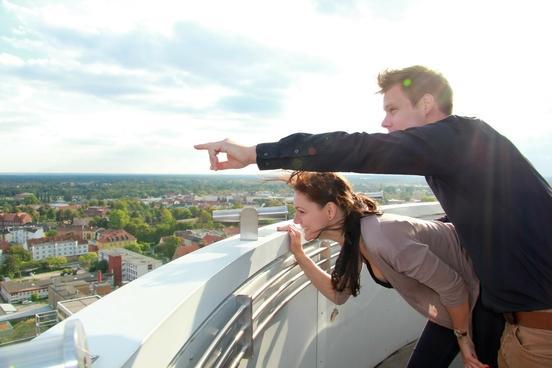 Zwei Menschen stehen auf einem Turm und schauen auf die Stadt hinunter