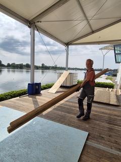 Mann schleppt Holzbalken