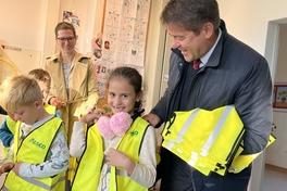 Oberbürgermeister Steffen Scheller hilft einer Schülerin bei der Anprobe der Sicherheitswarnweste.