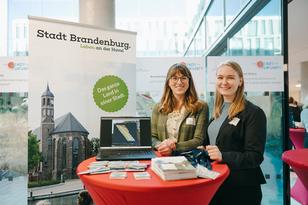 Zwei Mitarbeiterinnen der Stadt stellen an einem Stand das Projekt mit Plakaten und Flyern vor.