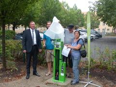 Vier Personen nehmen eine Abdeckung von Fahrrad-Reparatur-Station herunter