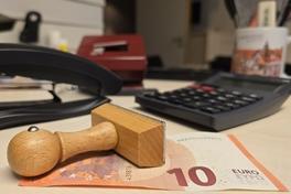 Schreibtisch mit Geldscheinen und Stempel