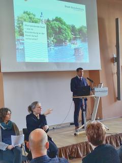 Der Oberbürgermeister am Rednerpult, davor sitzt Publikum und zwei Gebärdendolmetscherinnen