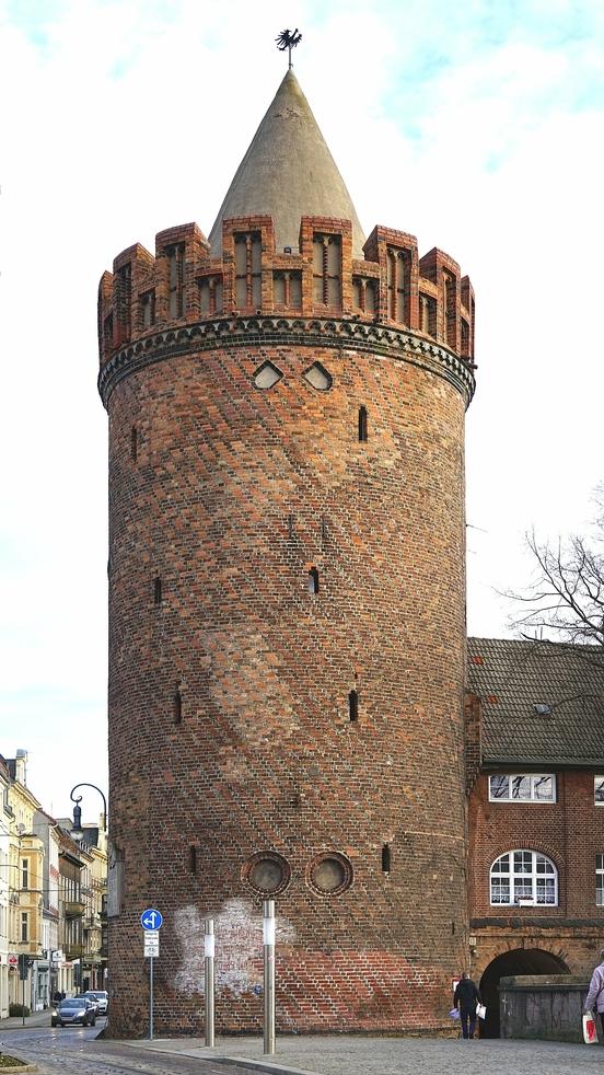 Steinturtorm in Brandenburg aus Backstein. Runder Turm mit wenigen kleinen Fenstern und spitzem Dach. 