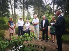 Personengruppe steht um ein Grab im Halbkreis