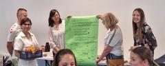 3 Lehrerinnen präsentieren ein grünes Plakat mit Danksagungen und Unterschriften