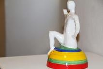 Plastik von einem Menschen, der auf einem fabrigen Podest sitzt.