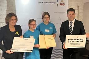 Vier Personen mit Urkunde, Scheck und Auszeichnung