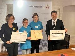 Vier Personen mit Urkunde, Scheck und Auszeichnung