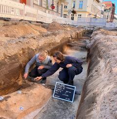 2 hockende Personen arbeiten mit Spateln an dem mittelalterlichen Körpergrab.