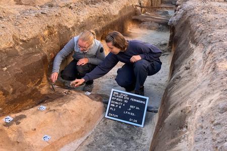 2 hockende Personen arbeiten mit Spateln an dem mittelalterlichen Körpergrab.