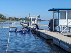 Sportler in Kanus an einem schwimmenden Steg der Regattastrecke