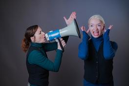 Eine Frau hält ein Megaphone in derv Hand und macht einer anderen eine Ansage.