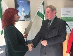 Die Sozialministerin übergibt eine Urkunde an den Preisträger