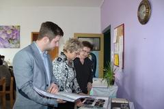 Oberbürgermeisterin, Geschäftsführer und Kita-Leiterin blättern in den Chronikalben.