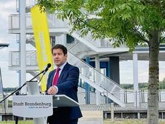 Steffen Scheller am Rednerpult vor dem Gebäude der Regattastrecke