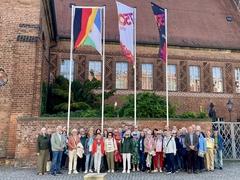 Gruppenbild vor Flaggen und Rathaus.
