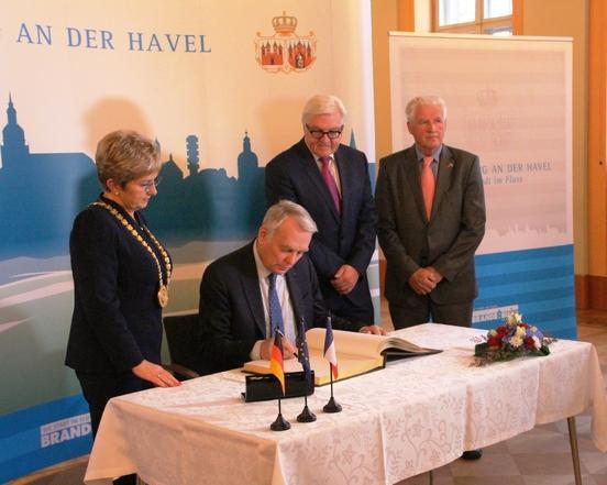 Der französische Außenminister Jean-Marc Ayrault trägt sich neben Frank-Walter Steinmeier und Oberbürgermeisterin Dietlind Tiemann sowie SVV-Vorsitzendem Walter Paaschen ins Goldene Buch der Stadt ein.