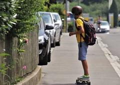Junge auf einem Skateboard mit Helm und Rucksack auf dem Rücken auf einer Straße.