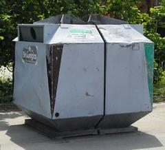 Ein Glascontainer für Grün-und Braunglas steht in der Sonne. Im Hintergrund Bäume.