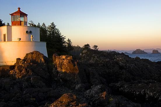 Fotografie eines Leuchtturmes, der an einer felsigen zerklüfteten Küste steht.