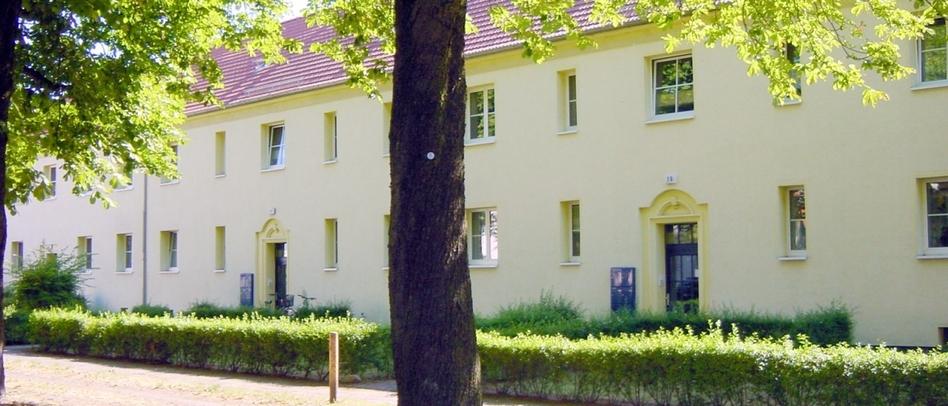 2-stöckiges Wohnhaus mit mehreren Eingängen an einem begrünten Weg