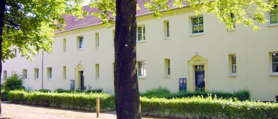 2-stöckiges Wohnhaus mit mehreren Eingängen an einem begrünten Weg