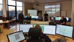 Viele Mitarbeiter im großen Raum. Ein paar stehen und ein paar sitzen am Rechner