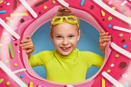 Ein Mädchen schaut durch einen großen Schwimmreifen.