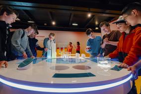 Jugendliche stehen um ein Exponat aus der Ausstellung MS Wissenschaft