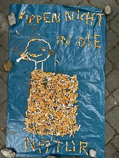 Buchstaben und Figur aus Zigarettenkippen