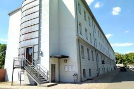 weißes Gebäude mit eingemauertem Aufzugschacht an der Stirnseite