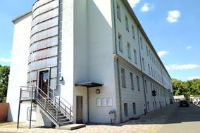 weißes Gebäude mit eingemauertem Aufzugschacht an der Stirnseite