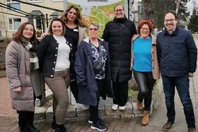 Gruppenbild 7 Personen 6 Frauen 1 Mann vor Schild