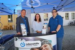 Stand der Lebenshilfe mit drei Personen.