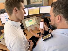 zwei Männer schauen auf ein Handy, auf dem Display ist "Medizinischer Notfall" zu lesen