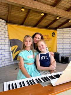 Lehrerin Anna Zadorozhna mit zwei ihrer Schützlinge auf der Gartenbühne der Musikschule.