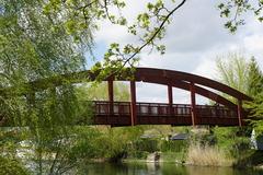 Die Näthewindebrücke im Sommer: Am Bildrand ragen belaubte Äste ins Bild, die Rote Bogenbrücke Näthewinde führt von rechts nach Links