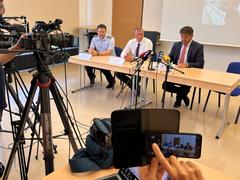 Kameras, die auf die drei Personen am Tisch gerichtet sind