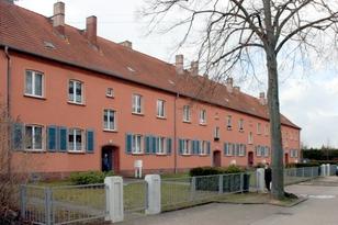 2-stöckiges Wohnhaus mit mehreren Eingängen an einem begrünten Weg
